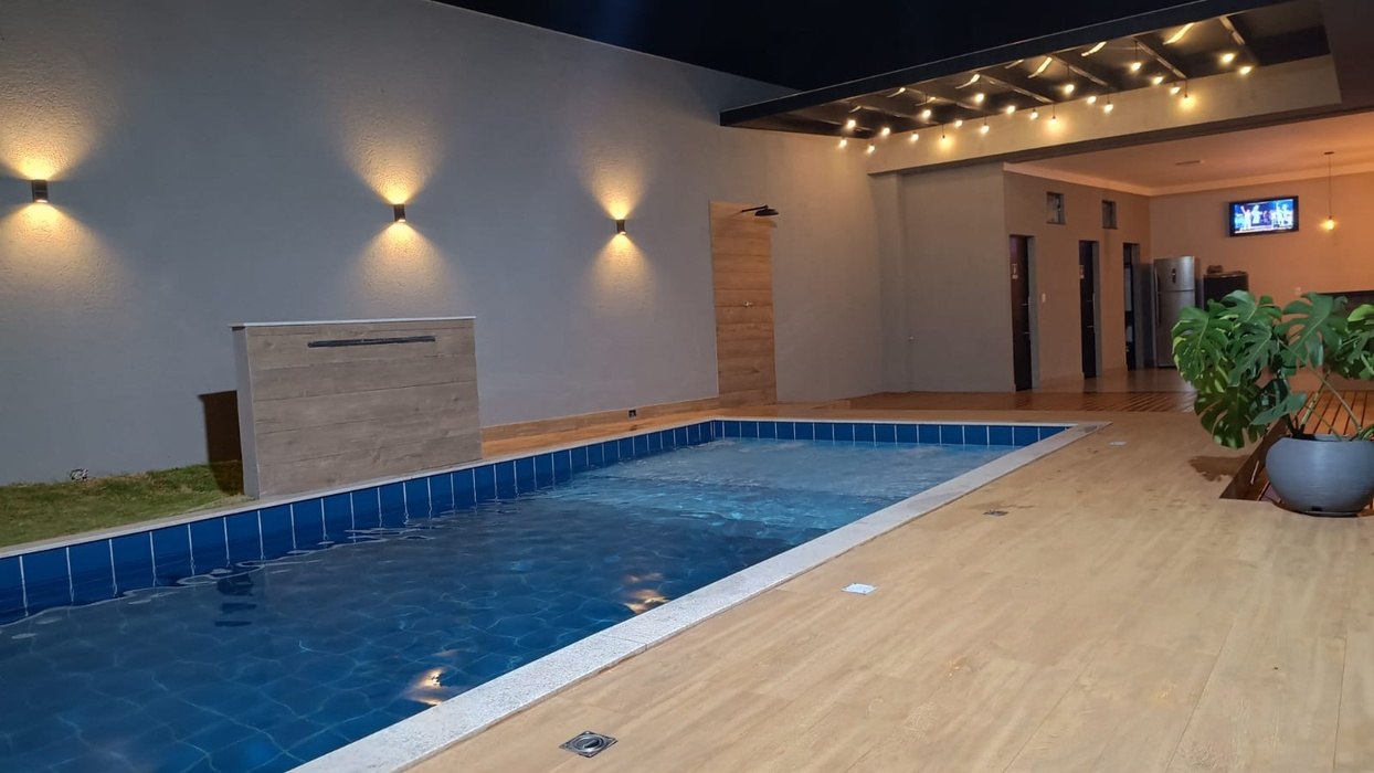 A mesma piscina à noite, com a iluminação interna acesa