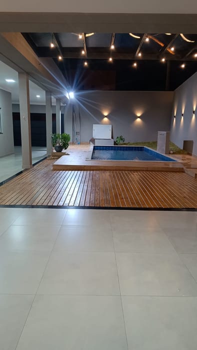 O salão coberto à noite, de frente para a piscina