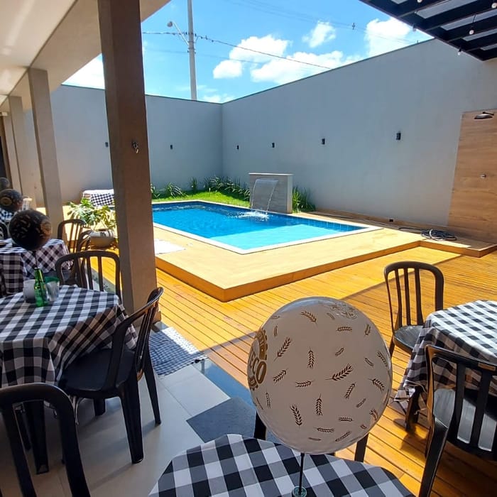 Mesas postas para uma festa, com a piscina do lado